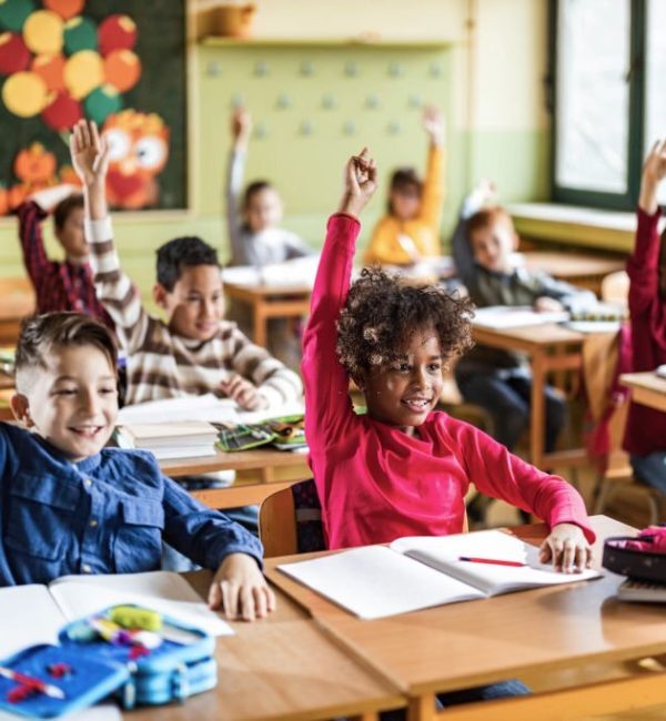 Large group of happy elementary students know the answer on a class in the classroom. Focus is on black girl.